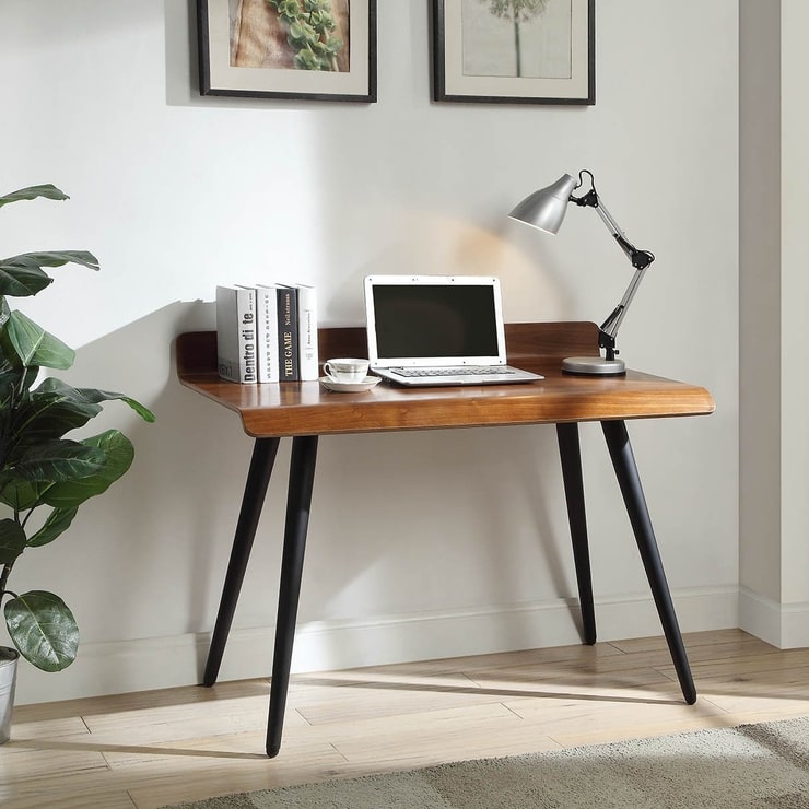 A retro walnut desk by Jual with a laptop on it and some books and an adjustable metal table lamp, set against a grey background