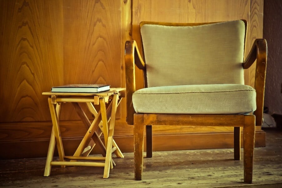 wood framed accent chair next to a wooden fold away combination stool and side table