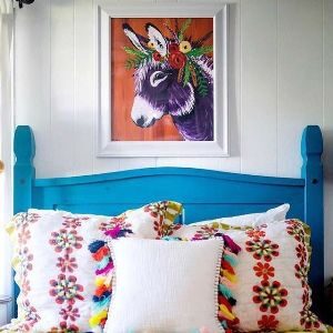 blue bedhead with cushions stacked against and picture of a donkey above