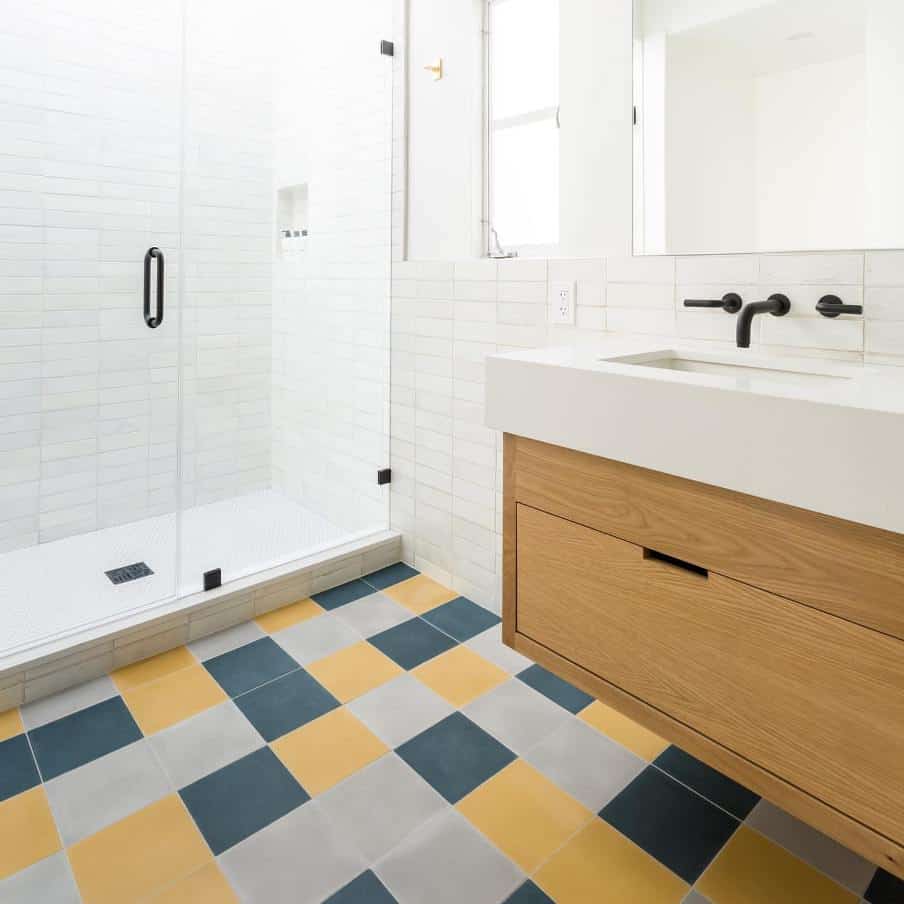 a white bathroom with oak sink furniture and multi colored floor tiles