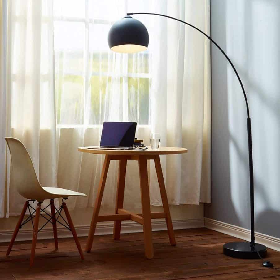 dark colored arch floor lamp over a small table and chair