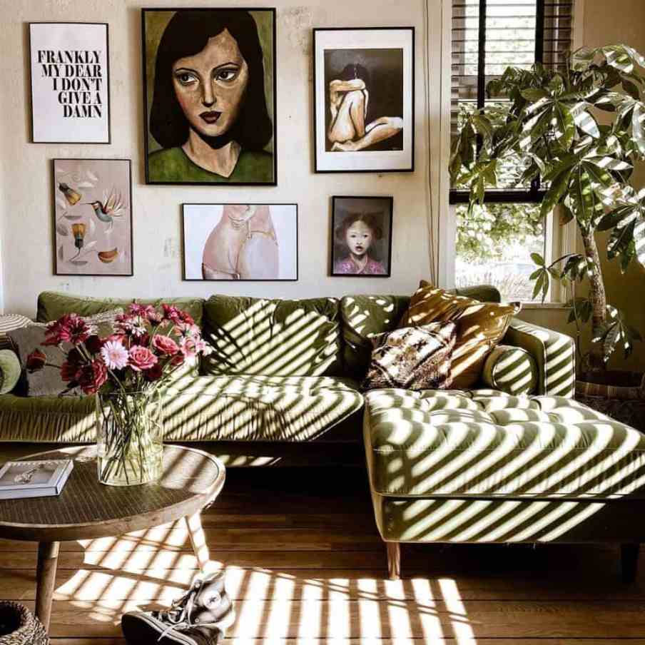 green velvet sofa with a wall of art behind