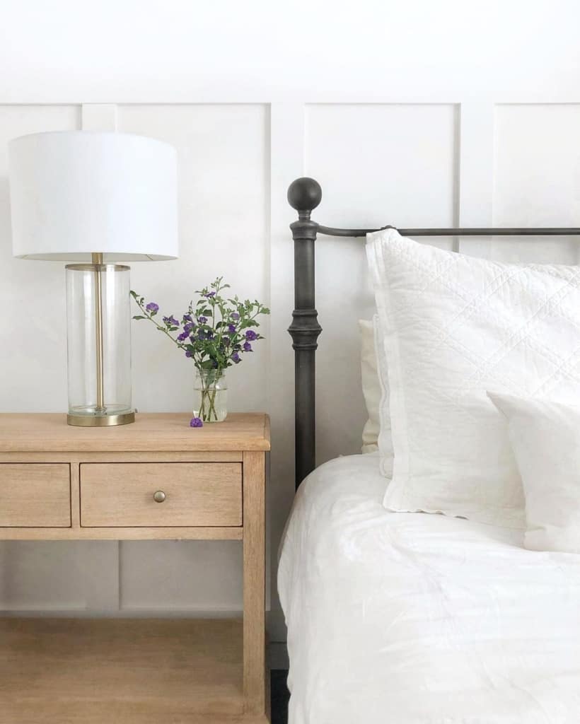 metal bedframe with white bedding and wooden nightstand