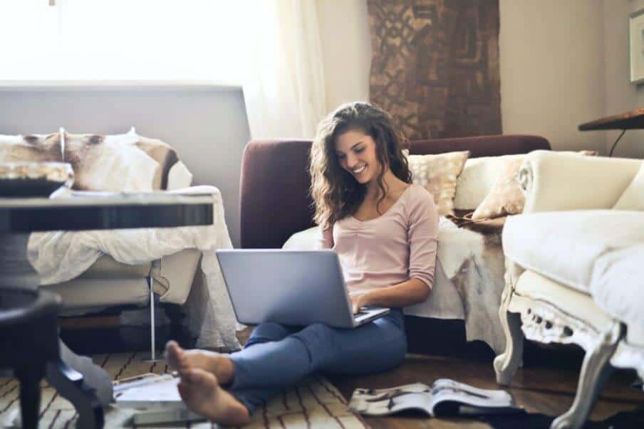a woman sitting on the floor looking at her laptop