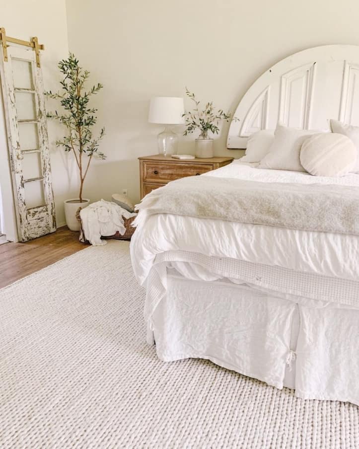white bedroom with rug and plant