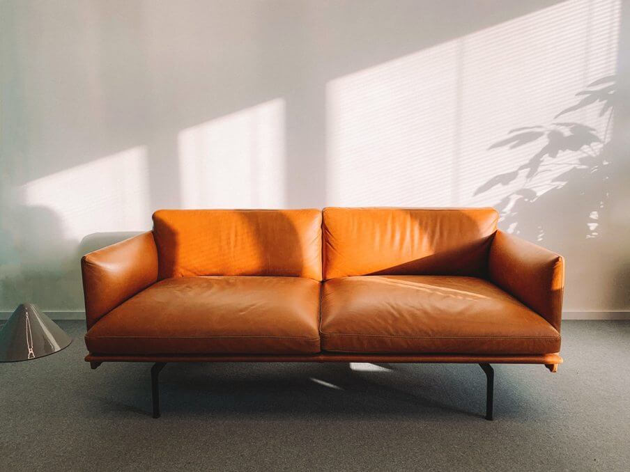 an orange leather sofa with sunlit wall behind