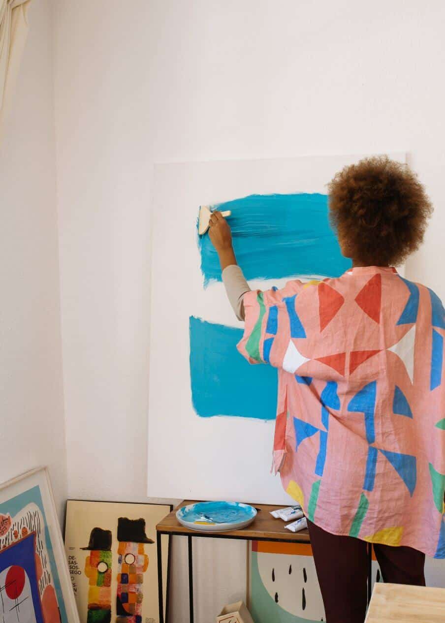 woman painting blue sample areas on wall