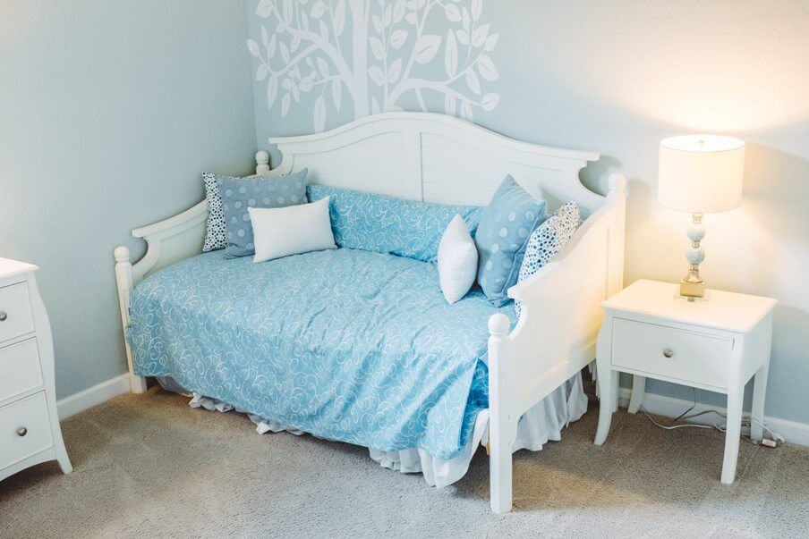 small daybed with blue cover in a bedroom setting with light blue walls